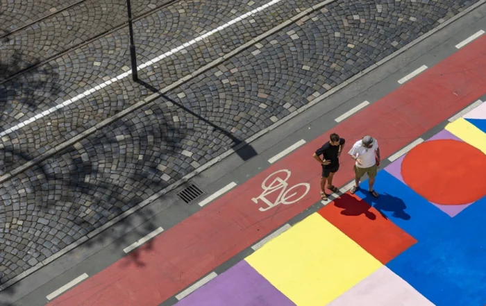 Urban Sports Park: Zwei Personen betrachten bemalte Bodenflächen mit geometrischen Formen in verschiedenen Farben.