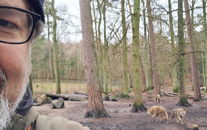 Selfie im Tierpark mit Wölfen im Hintergrund.