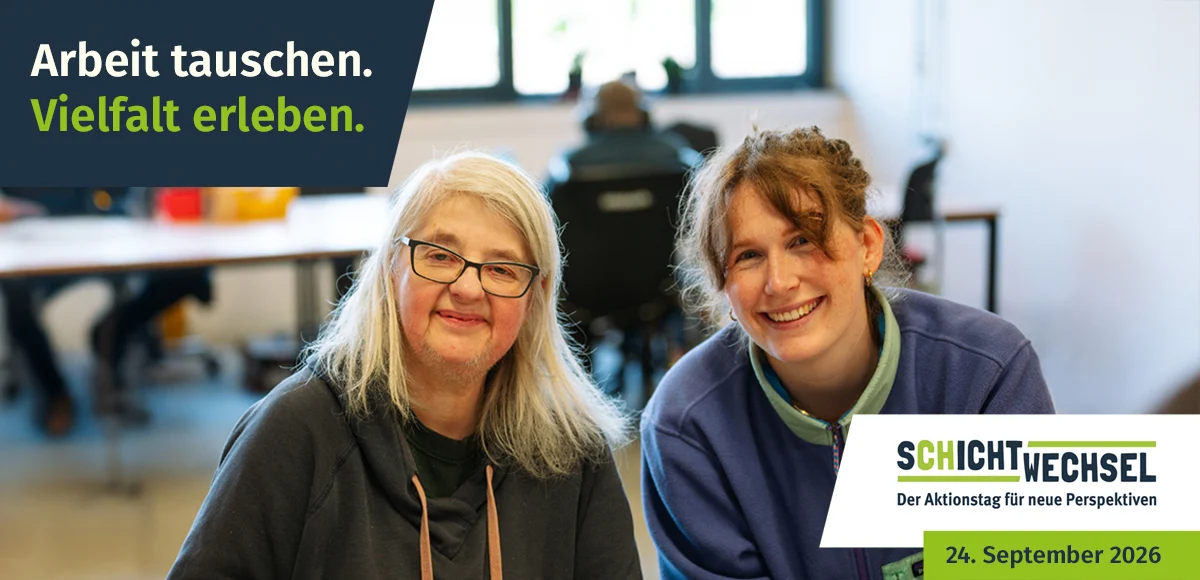 pw-aktuelles_schichtwechsel Zwei Frauen in einem Arbeitsraum einer Werkstatt blicken freundlich in die Kamera.