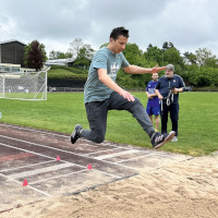 Ein Mann springt auf Sand.