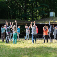 Menschen stehen im Kreis und strecken sich.