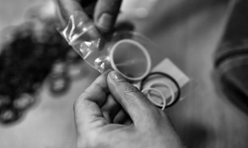 pw-konfektionierung-kachel Hände stecken verschiedene Ringe in eine Plastiktüte.