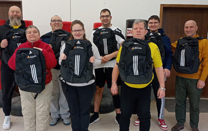 Sportler zeigen ihre neuen Rucksäcke.